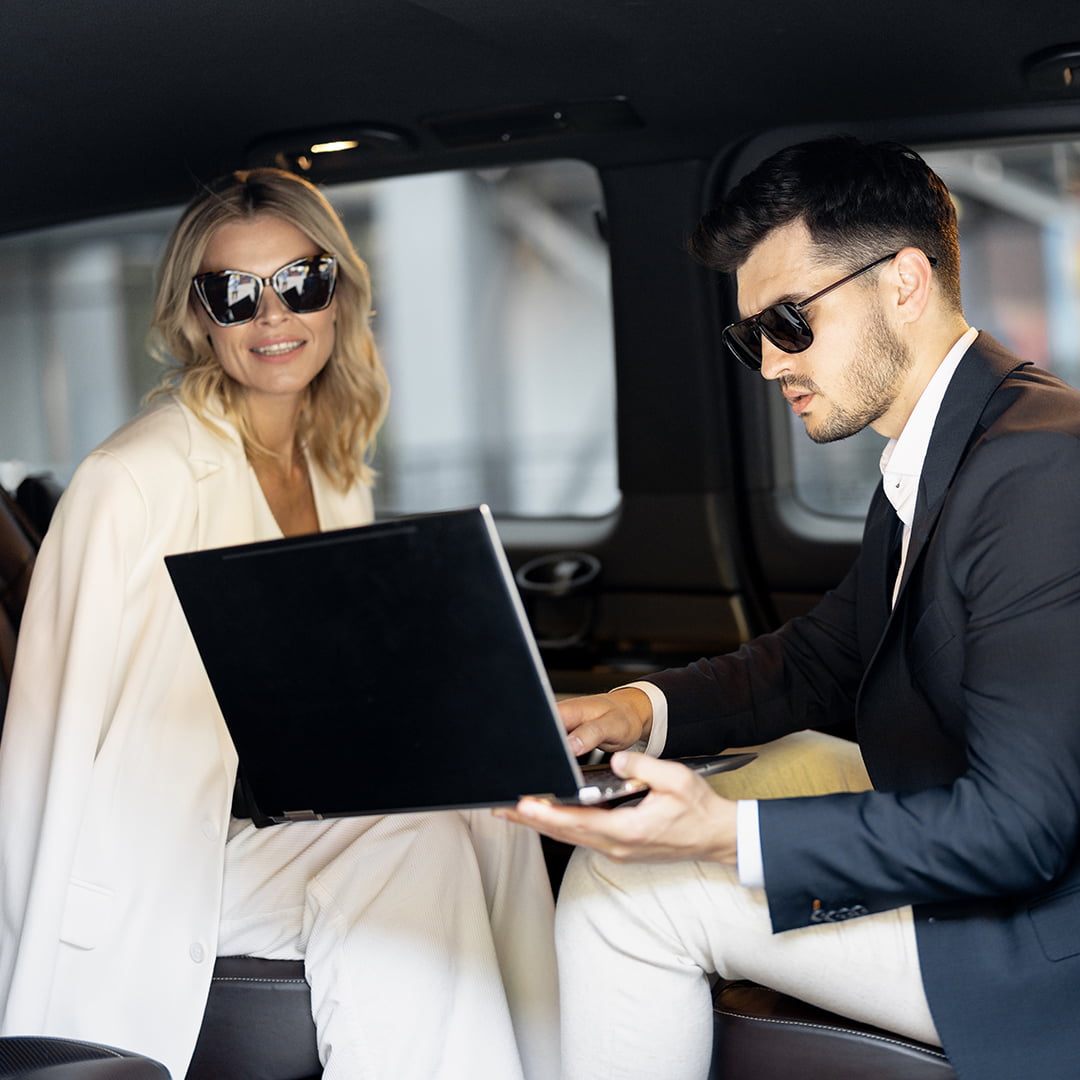 Business professionals working on a laptop in a Limostop luxury vehicle, combining comfort, style, and productivity for events